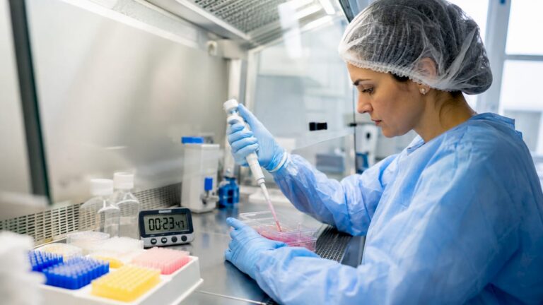 Lab technician performing sterile pipetting in biosafety cabinet